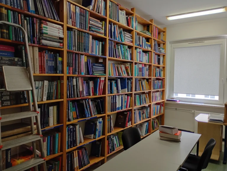 Wnętrze biblioteki. Regały z książkami, stół i krzesła.