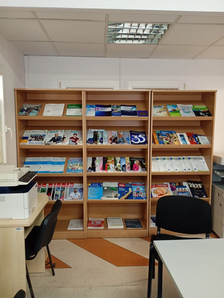 Wnętrze biblioteki. Regały z książkami, skaner, stół i krzesła.