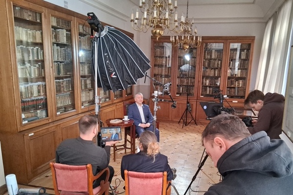 Sala na Jazdowie jako studio nagrań. Kamery, sprzęt, przygotowanie do nagrań. Na krzesłach siedzą ludzie.