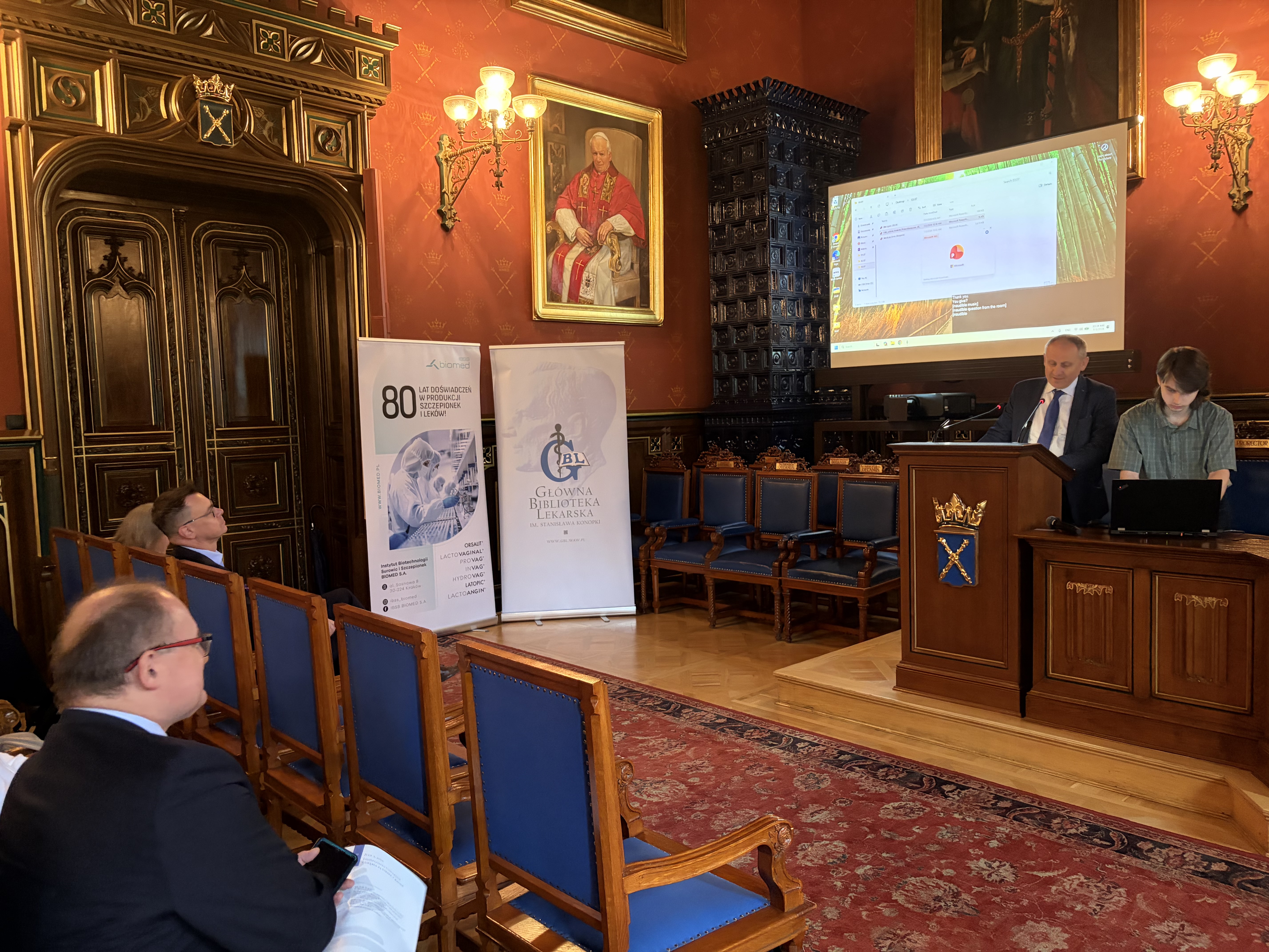 Klasyczna sala konferencyjna. Z podestu przemawia Dyrektor GBL.