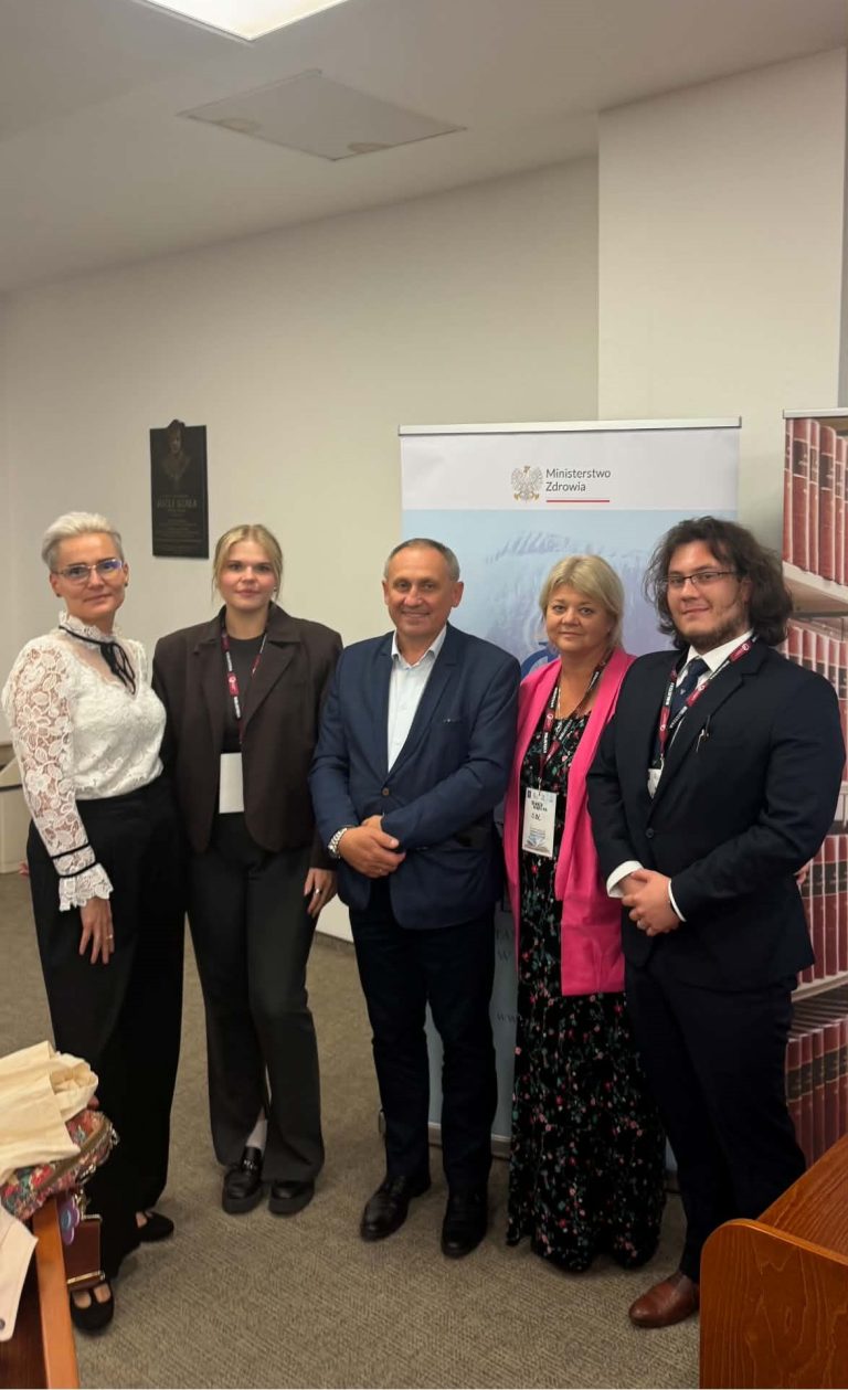Pamiątkowe zdjęcie grupowe pięciu uczestników konferencji stojących obok siebie w sali konferencyjnej na tle ścianki z logo Głównej Biblioteki Lekarskiej.