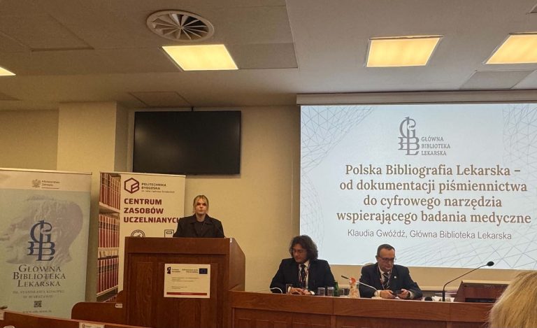 Prelegentka stoi przy drewnianej mównicy. Na ekranie w tle widnieje slajd prezentacji: „Polska Bibliografia Lekarska – od dokumentacji piśmiennictwa do cyfrowego narzędzia wspierającego badania medyczne”, autorstwa Klaudii Gwóźdź z Głównej Biblioteki Lekarskiej.